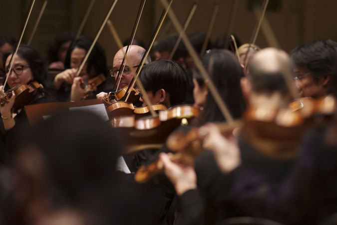 a sea of violins and violas with their bows pointing upwards at varying angles