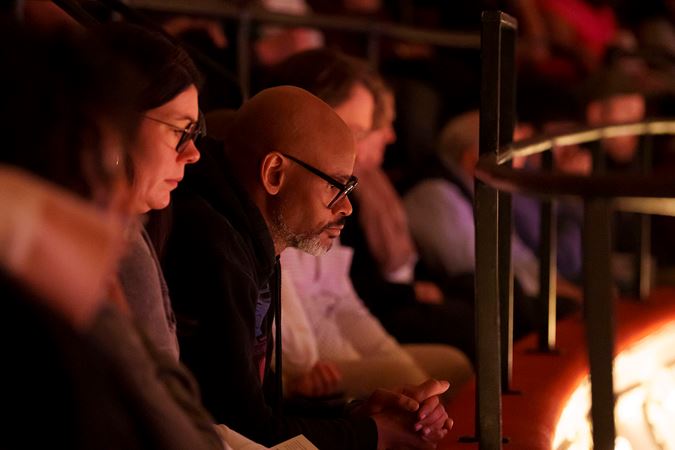 An audience member watches intently from the lower balcony