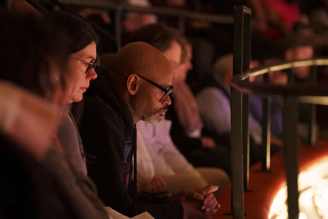 An audience member watches intently from the lower balcony