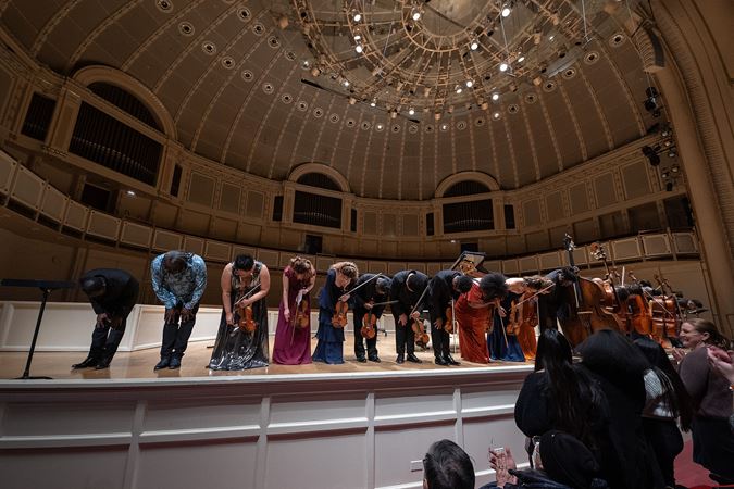 the full ensemble takes a bow as the audience rises to its feet