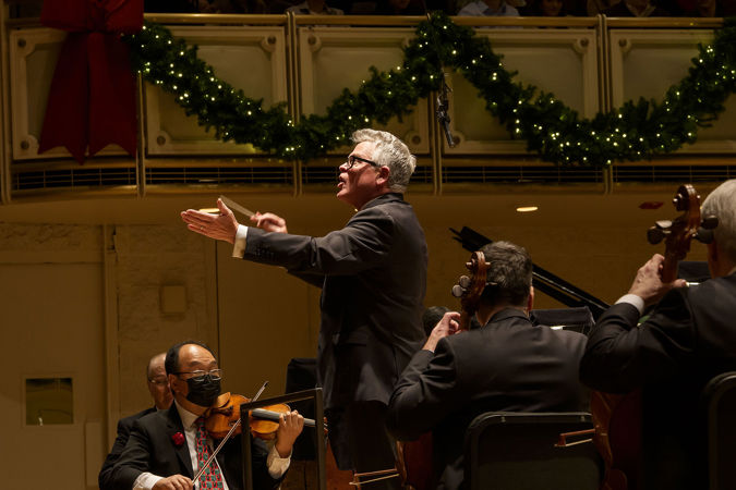 Closeup of John Morris Russell inviting audience members to singalong to a carol