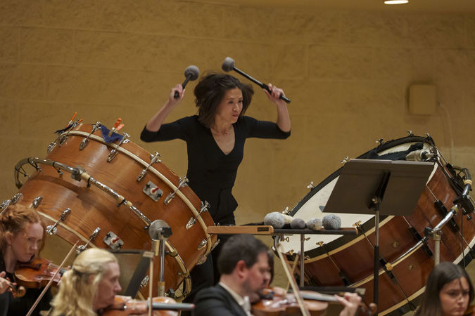 CSO principal percussion Cynthia Yeh rears back with a mallet in each hand, ready to simultaneously strike two bass drums