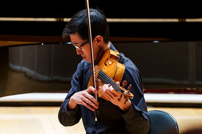 Closeup of CSO viola Danny Lai performing on stage