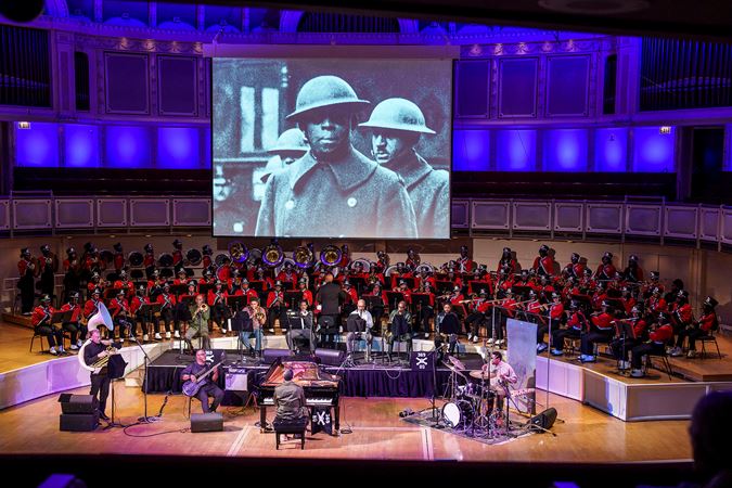 Wide of Jason Moran and accompanying musicians with a portrait of James Reese Europe projected on a screen