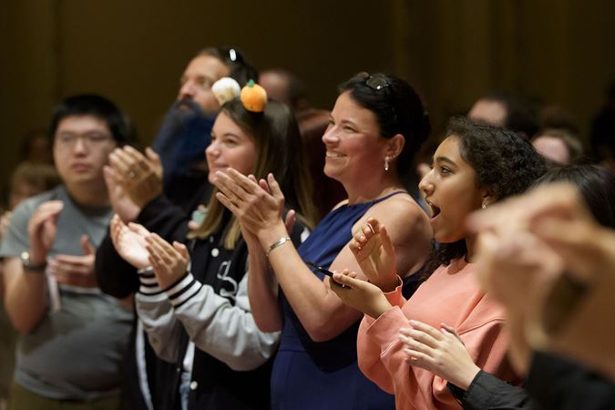 audience members on the main floor give a standing ovation