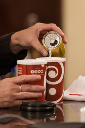 a close-up of a bartender's hand pouring soda into a CSO-branded cup