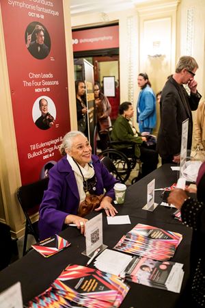 CSO African American Network board member Susan Carlotta Ellis greets attendees at a table in the lobby before the concert