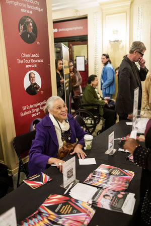 CSO African American Network board member Susan Carlotta Ellis greets attendees at a table in the lobby before the concert