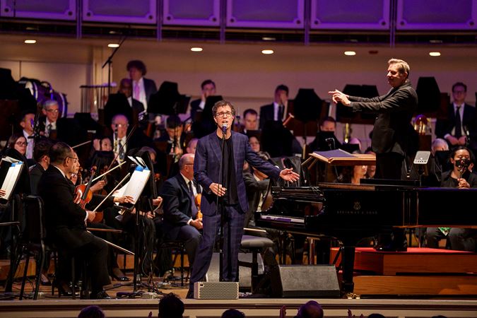 Wide shot of singer-songwriter Ben Folds singing on stage with the CSO and conductor Steven Reineke