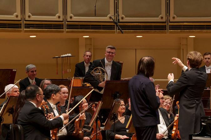 conductor Klaus Mäkelä gestures to CSO Principal Horn Mark Almond to take a solo bow
