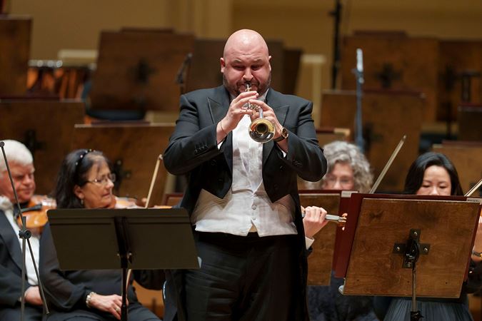 Closeup action shot of CSO principal trumpet Esteban Batallán performing on stage