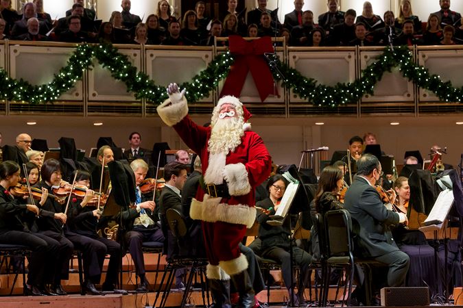 Closeup of Santa Claus on stage waving to the audience in Orchestra Hall