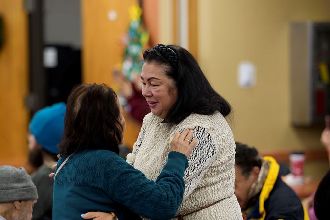Two community members from the Southwest Regional Senior Center hugging during the 2025 Civic Bach Marathon concert