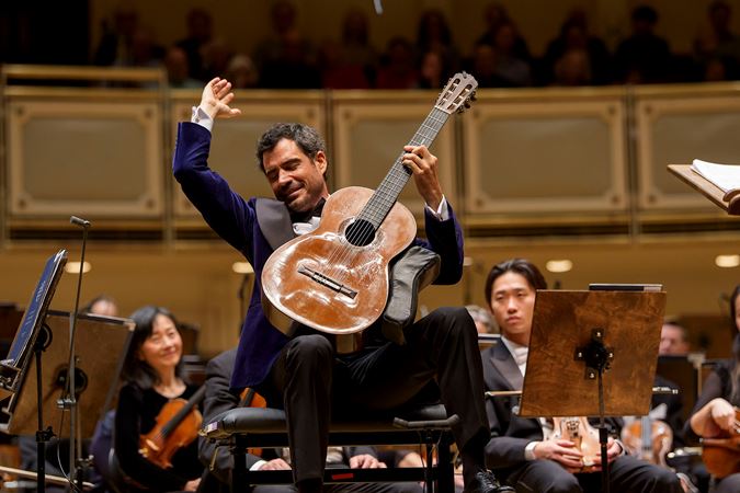 Classical guitarist Pablo Sáinz-Villegas strikes a final chord with hand raised high above his instrument