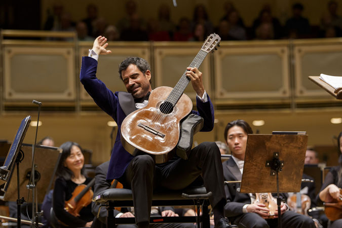 Classical guitarist Pablo Sáinz-Villegas strikes a final chord with hand raised high above his instrument