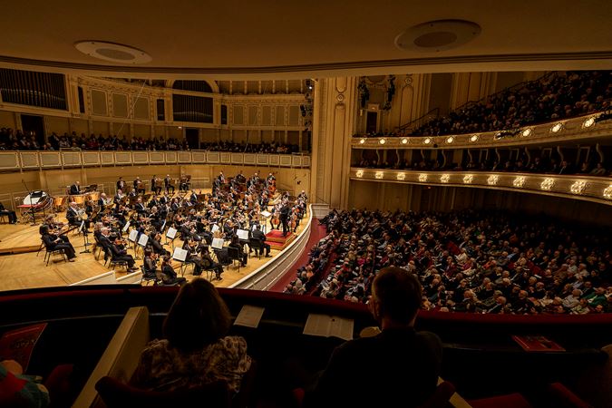 a point of view of audience members watching the Orchestra performs Brahms' Fourth Symphony from the box level