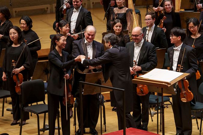 conductor David Afkham shakes the hand of associate concertmaster Stephanie Jeong