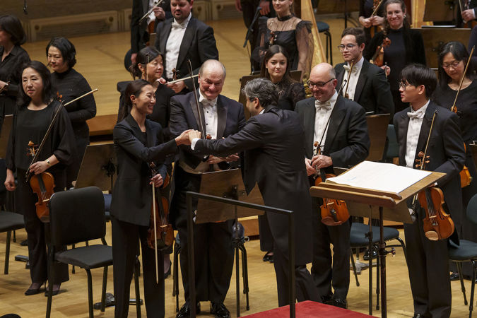 conductor David Afkham shakes the hand of associate concertmaster Stephanie Jeong