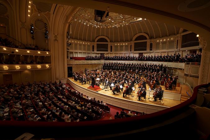 a view from the right side of the box level as Riccardo Muti raises his arms with vigor to signal the CSO and Chorus