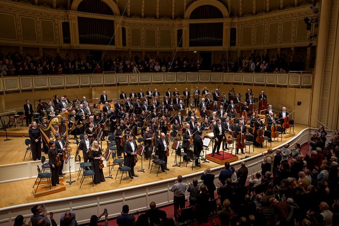 the full Orchestra takes a bow as audience members rise to their feet