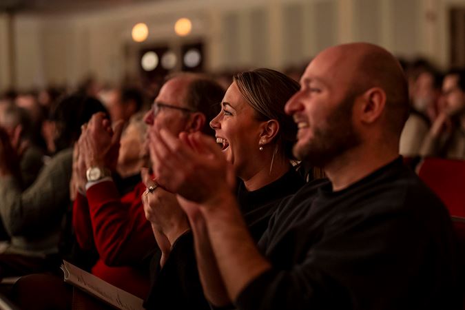 two audience members smile and clap enthusiastically after the performance