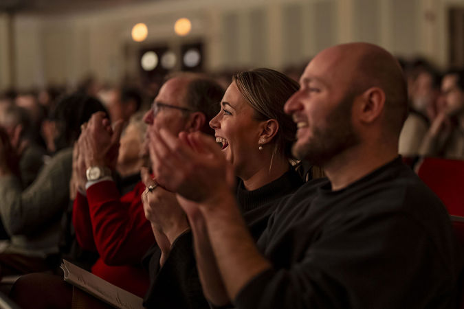 two audience members smile and clap enthusiastically after the performance