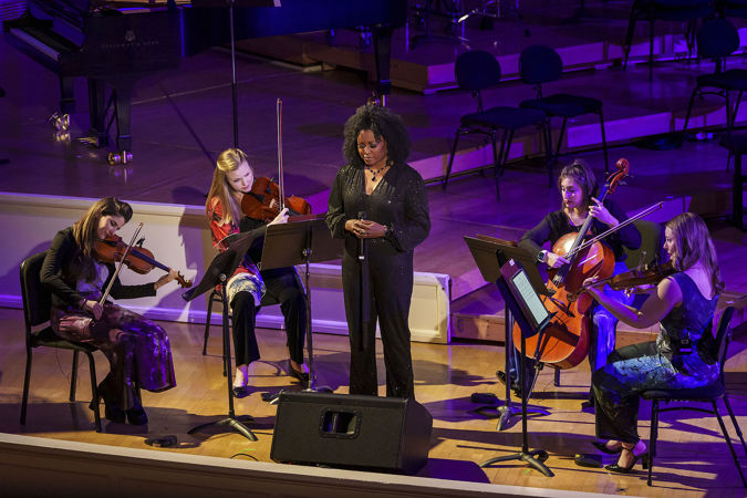 Wide shot of ensemble ATLYS and singer Simbryt Dortch performing a Notes for Peace tribute song