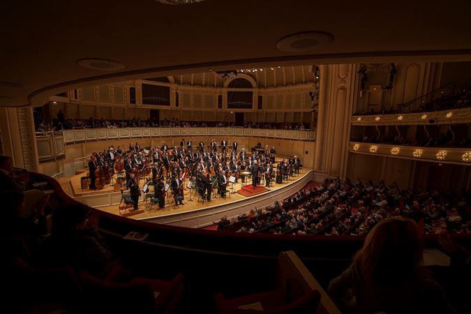 A wide shot of the CSO and conductor Sir Mark Elder bowing on stage