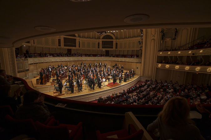 A wide shot of the CSO and conductor Sir Mark Elder bowing on stage