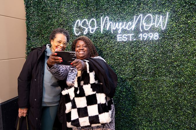 two people take a selfie in front of the MusicNOW sign