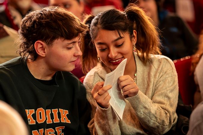 two students animatedly discuss the program before the concert