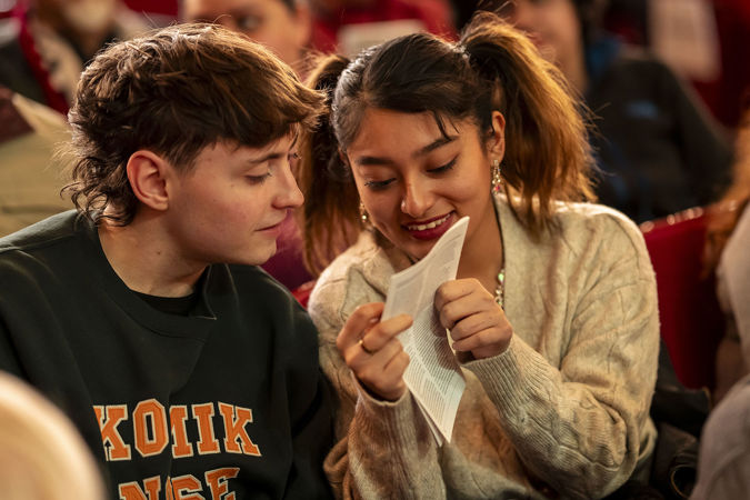 two students animatedly discuss the program before the concert