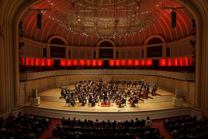 Wide shot of members on the CSO and conductor Daniel Bartholomew-Poyser performing on stage
