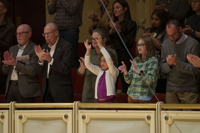 a group of audience members ranging from young to old finds common ground in the music as they rise in a standing ovation