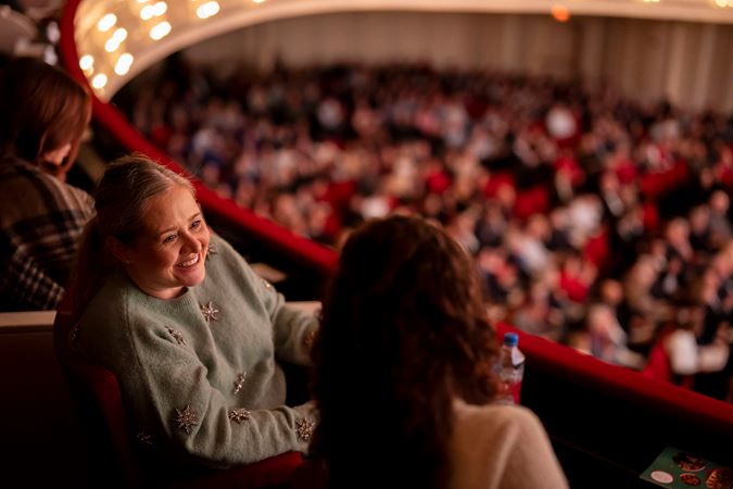 A closeup of a woman smiling to a friend in the box level