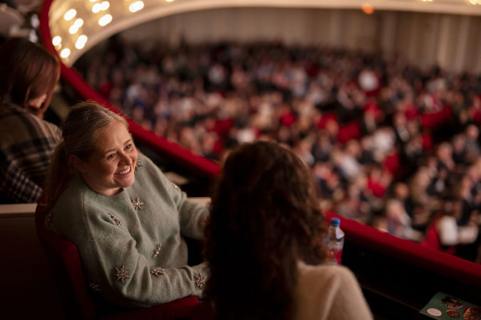 A closeup of a woman smiling to a friend in the box level
