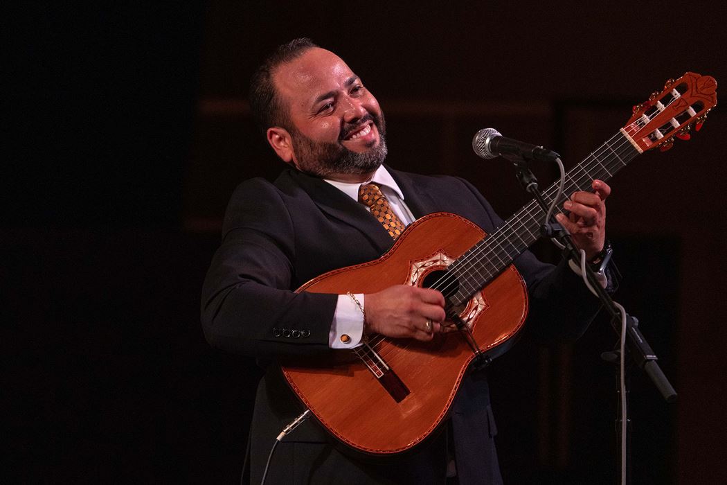 guitarist and vocalist Gabriel Rodriguez Ortiz, of the Puerto Rican-based group Trío Remembranza, smiles at the audience