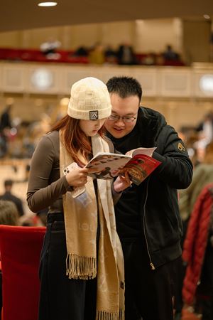 two young audience members, bundled from the cold, stand and read their programs before the concert begins