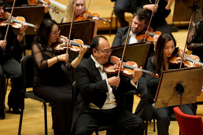 Closeup shot of CSO concertmaster Robert Chen smiling and performing on stage