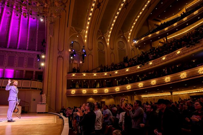 Chris Thile gives the audience a wave as they rise to their feet to give him an ovation
