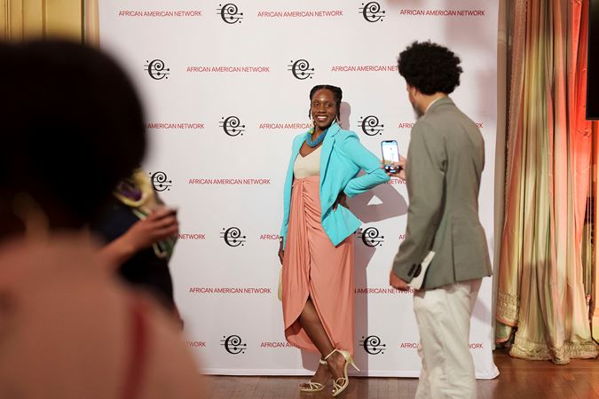 A CSO African American Network member takes a photo behind a CSO backdrop in Grainger Ballroom