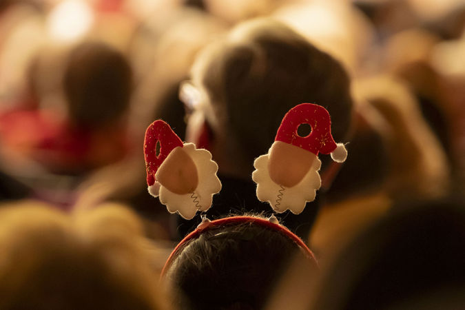 A closeup shot of a Santa Claus headband worn by a child sitting in the audience
