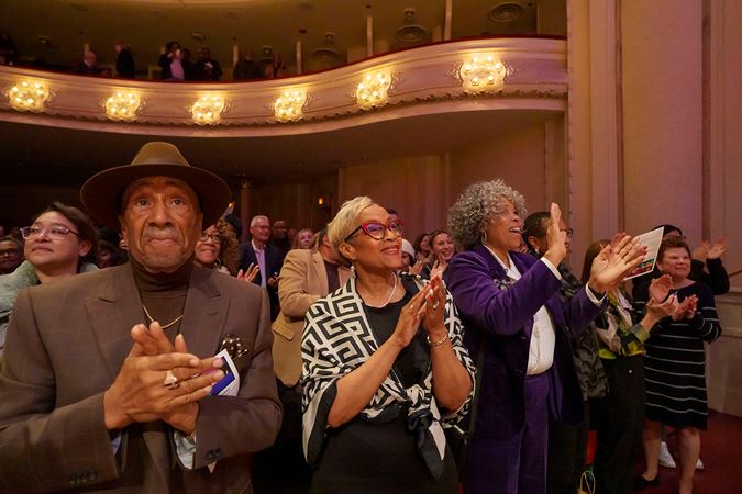 Audience members on the main floor give cheers and a standing ovation