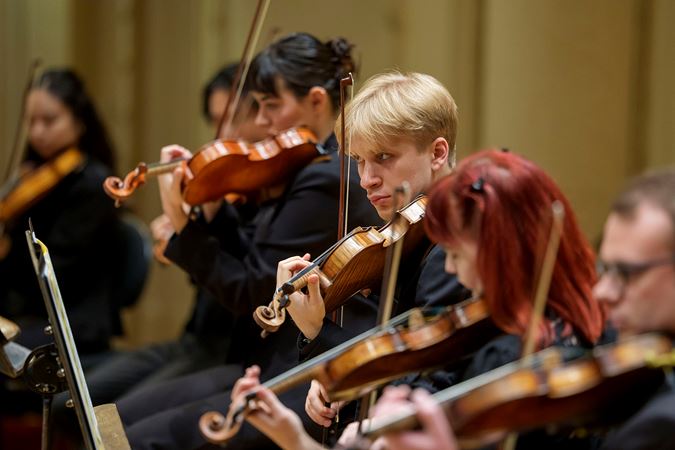 Group shot of Civic violinists warming up on stage