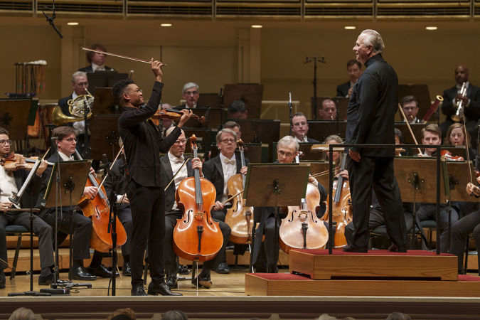 Group shot of violinist Randall Goosby, conductor Sir Mark Elder and several CSO cello musicians