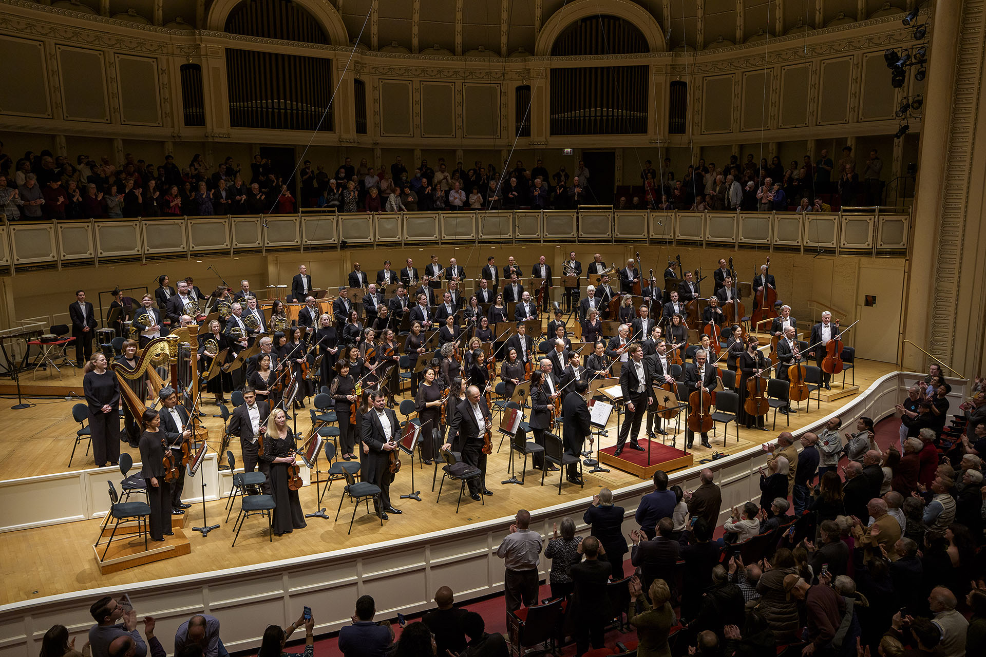 a view of Klaus Mäkelä and the CSO bowing from the left side of the box level