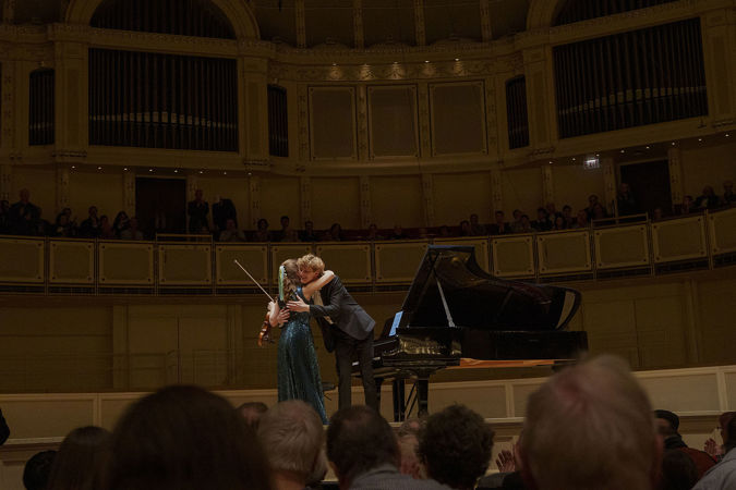 Violinist Julia Fischer and pianist Jan Lisiecki hugging on stage