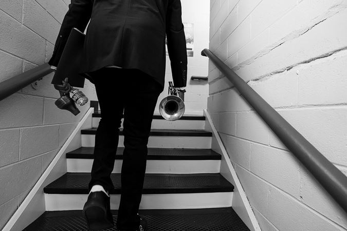 in black and white, trumpeter Sean Jones walks up the stairs backstage in Orchestra Hall from behind