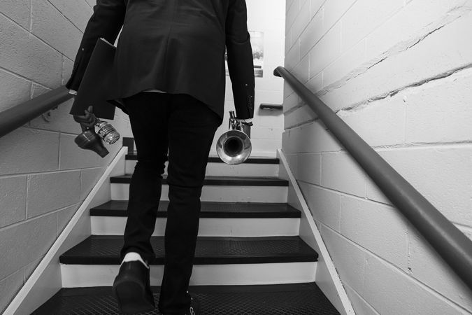 in black and white, trumpeter Sean Jones walks up the stairs backstage in Orchestra Hall from behind