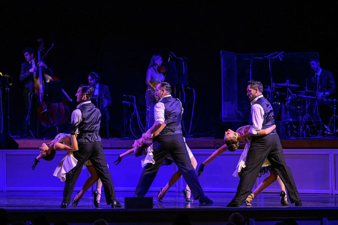 three tango couples dip their partners at the same time, creating a striking symmetrical picture